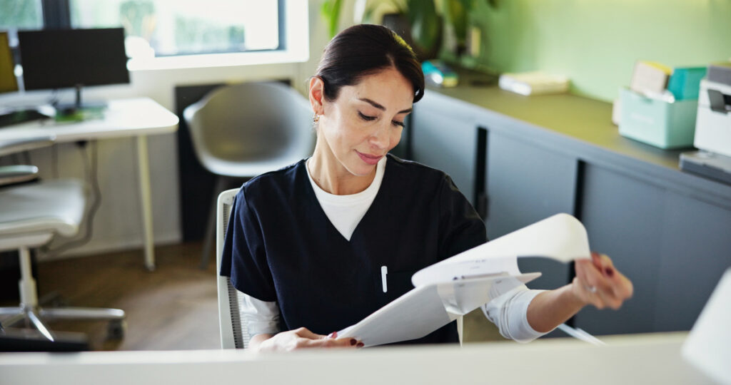 woman at dental reception looking at paperwork for digital lab case delays