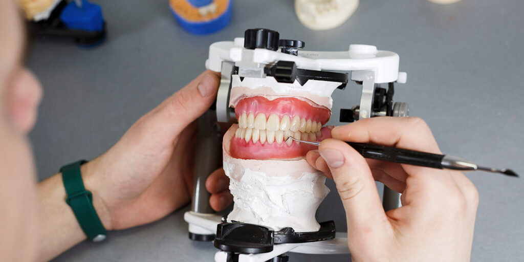 Dental lab worker moulding false teeth from digital scanning implants